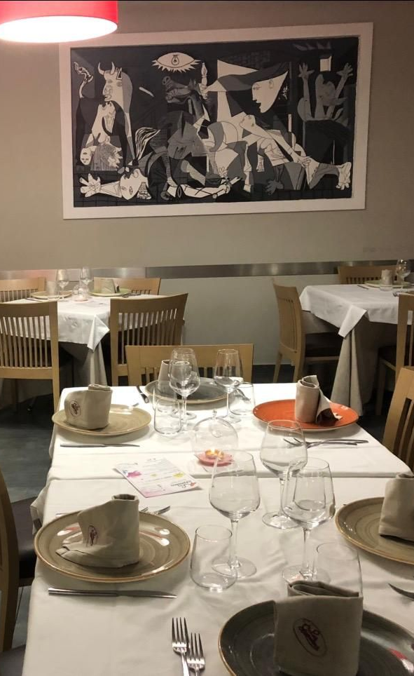 Antipasto di gamberi servito su un supporto di legno con guarnizione verde, in un ambiente da ristorante.