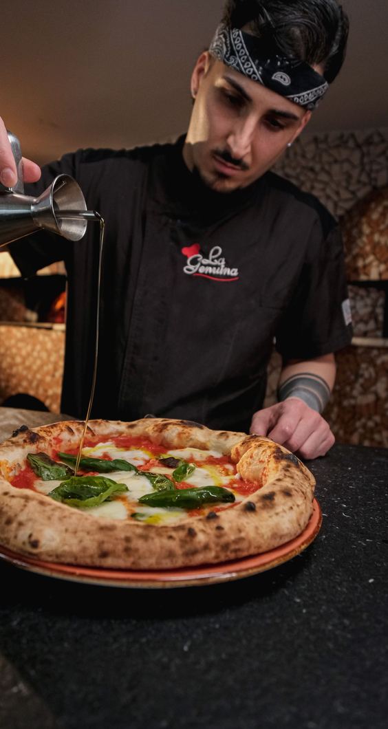 Primo piano di una pizza con formaggio fuso, cipolle rosse, verdure e carne rossa su una crosta dorata.