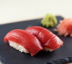 Sushi rolls on a black plate with pickled ginger and parsley on a wooden table