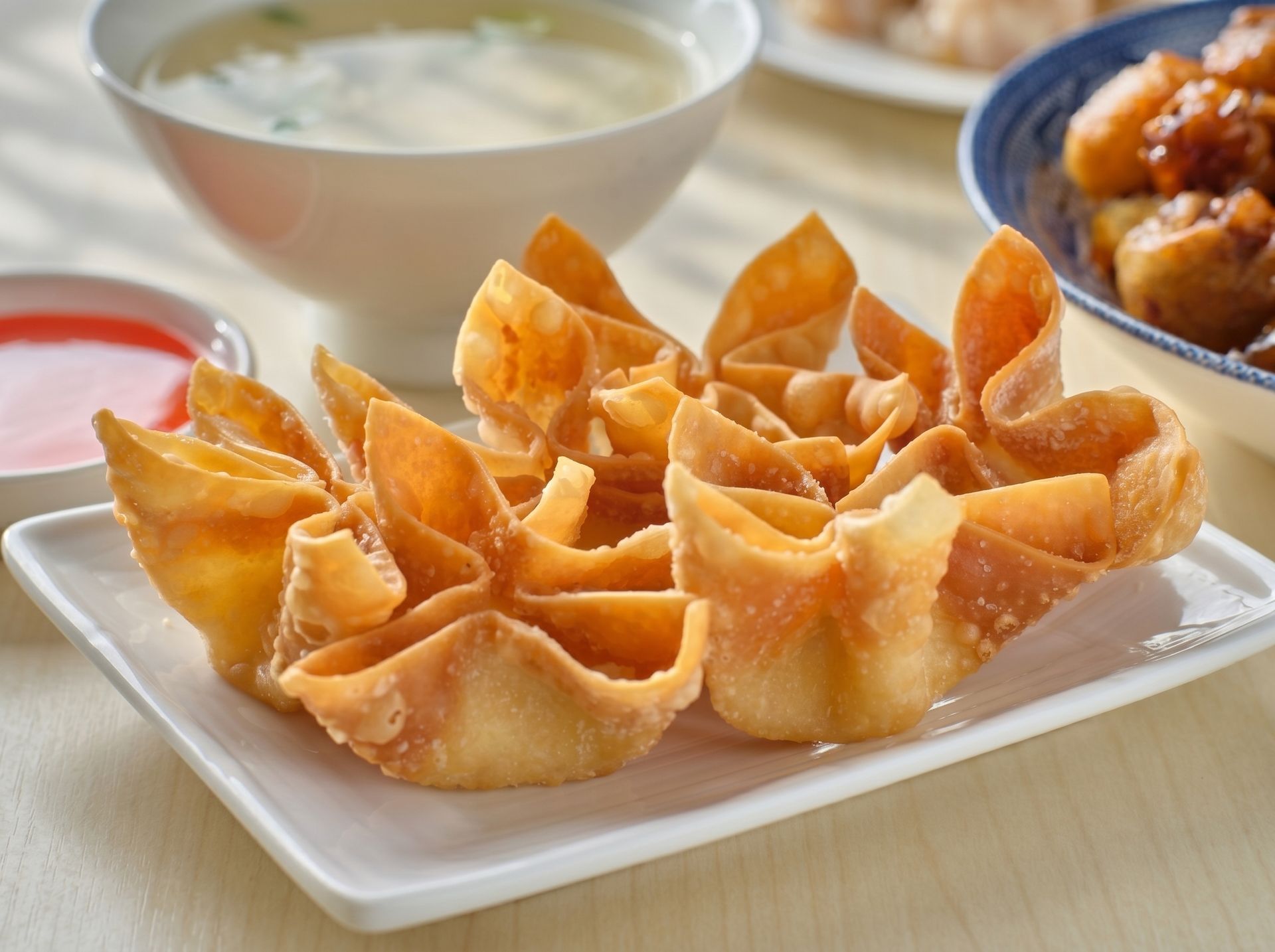 Plate of golden fried dumplings with dipping sauces on a table