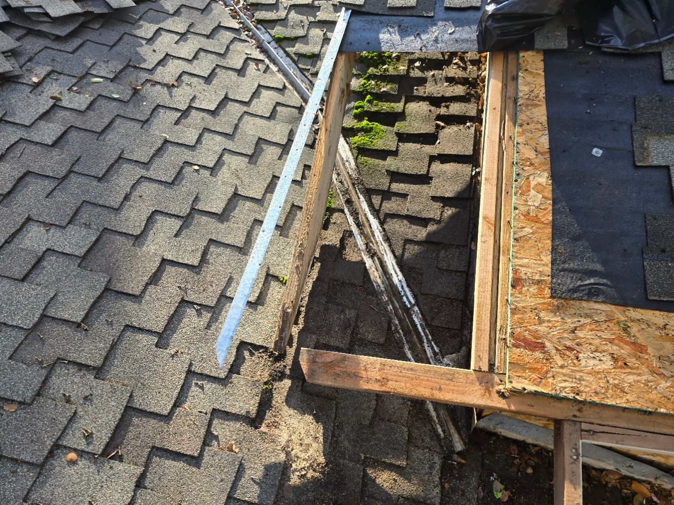 Damaged roof with missing shingles, exposed wood framing, and an open section near a chimney.