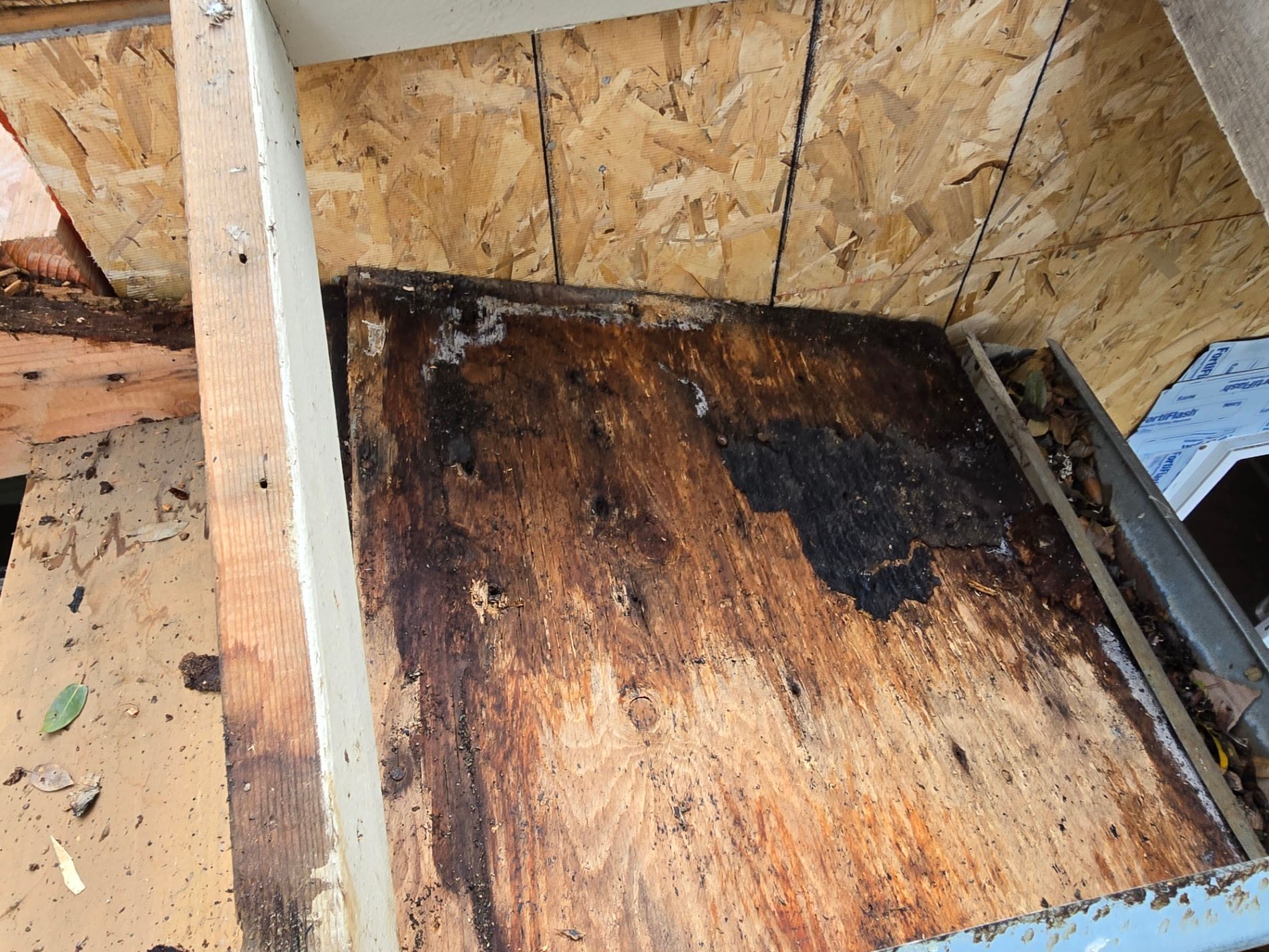 Charred plywood floor in an unfinished attic with exposed framing and plywood walls