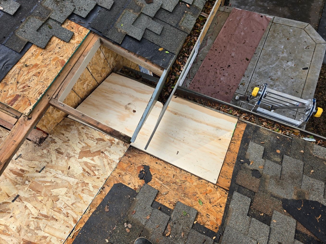 Rooftop repair with exposed plywood and roofing felt around a skylight opening
