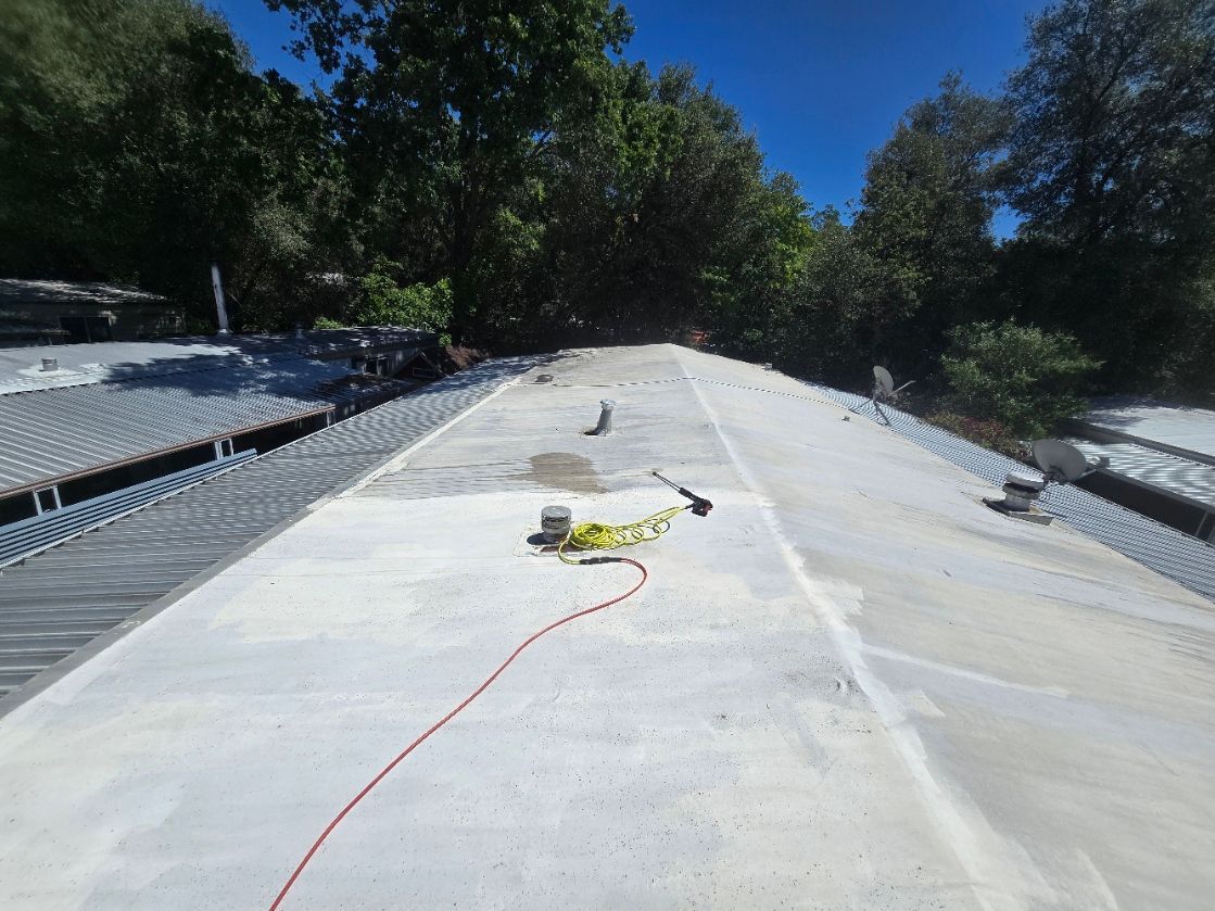 Concrete slope under construction with tools and cables, surrounded by trees under a blue sky