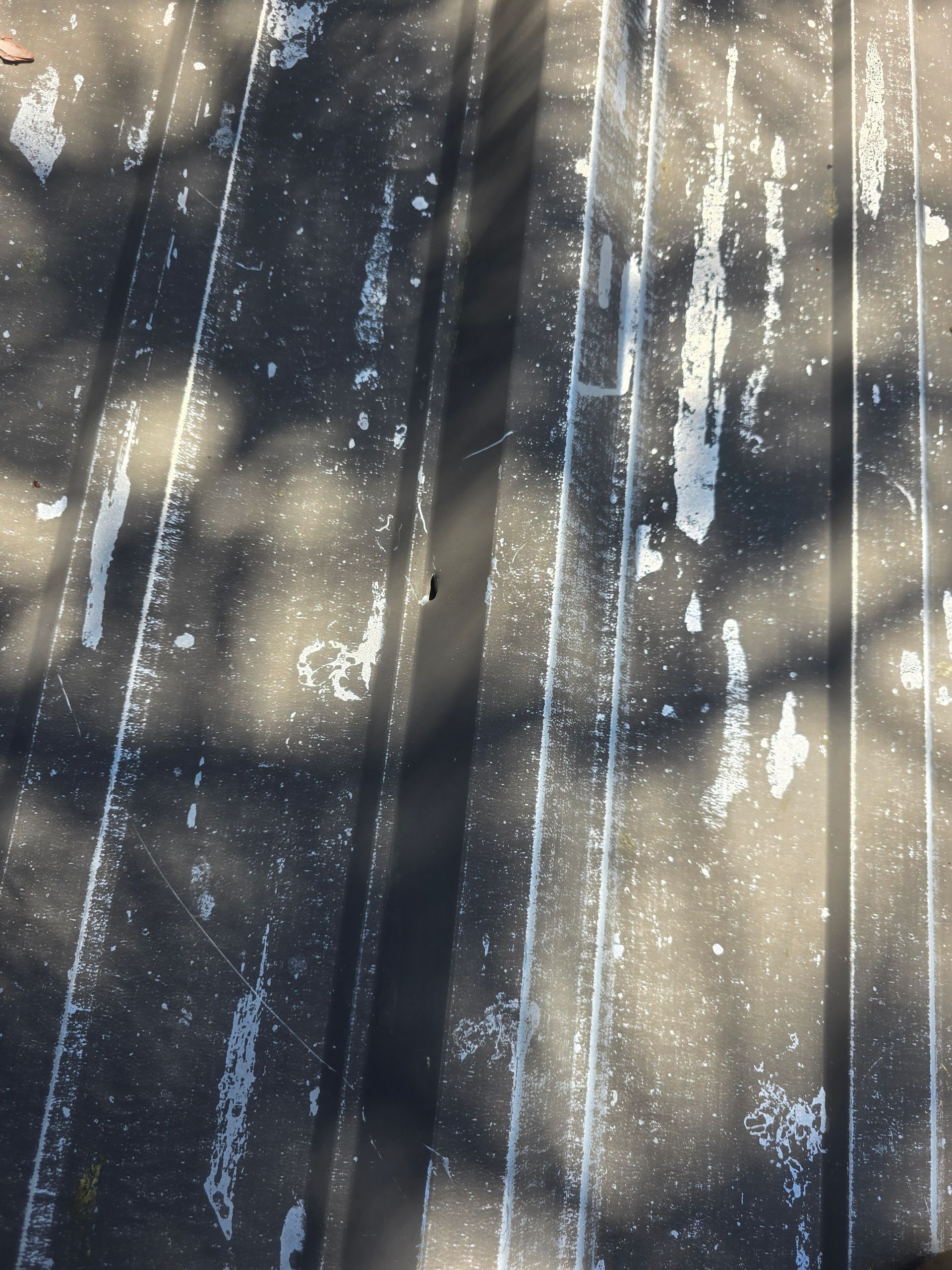 Sunlight and shadows on weathered wooden planks with white paint streaks