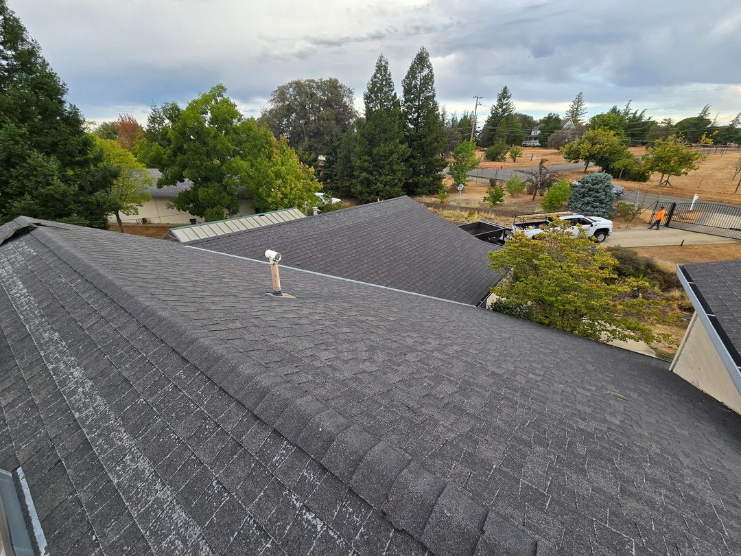 Gray shingled rooftops overlooking a tree-lined suburban neighborhood under cloudy skies