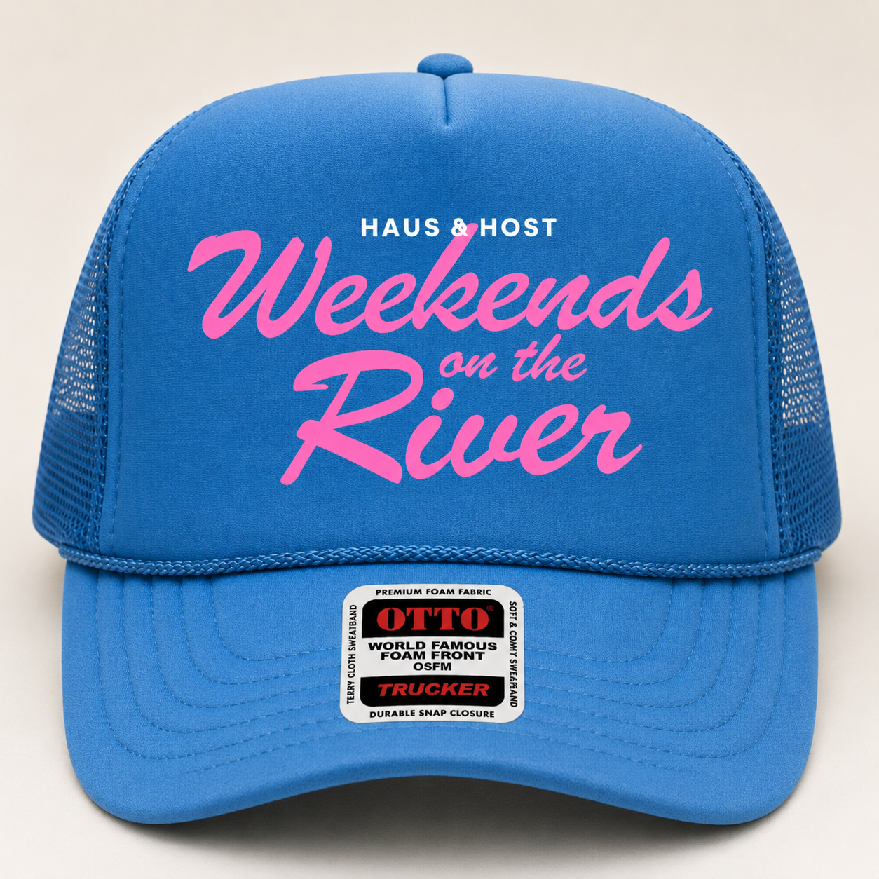 Blue trucker cap with pink “Weekends on the River” text and a small “Haus & Host” logo.
