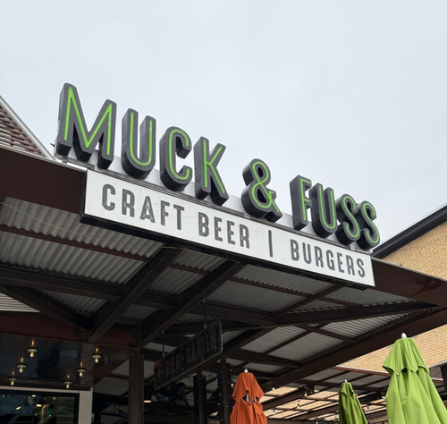 Muck & Fuss restaurant sign above patio, with