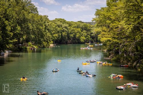 People kayaking on a calm green river surrounded by lush trees
