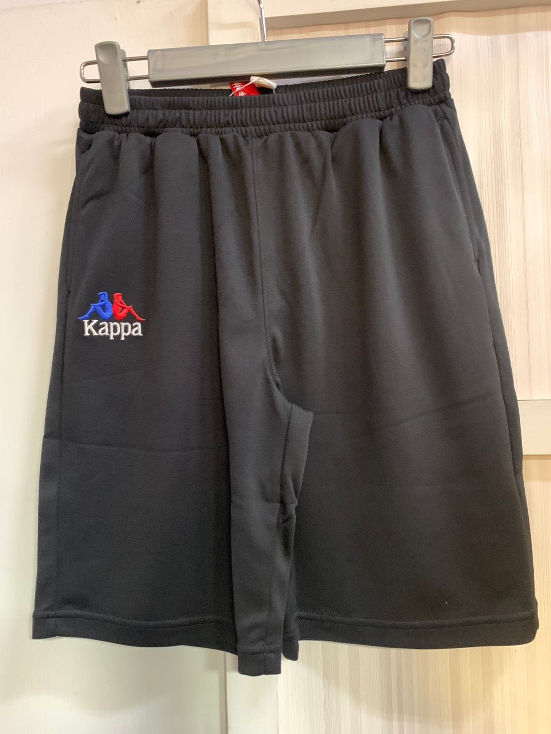 帶有標誌的黑色 Kappa 運動短褲，掛在衣架上。