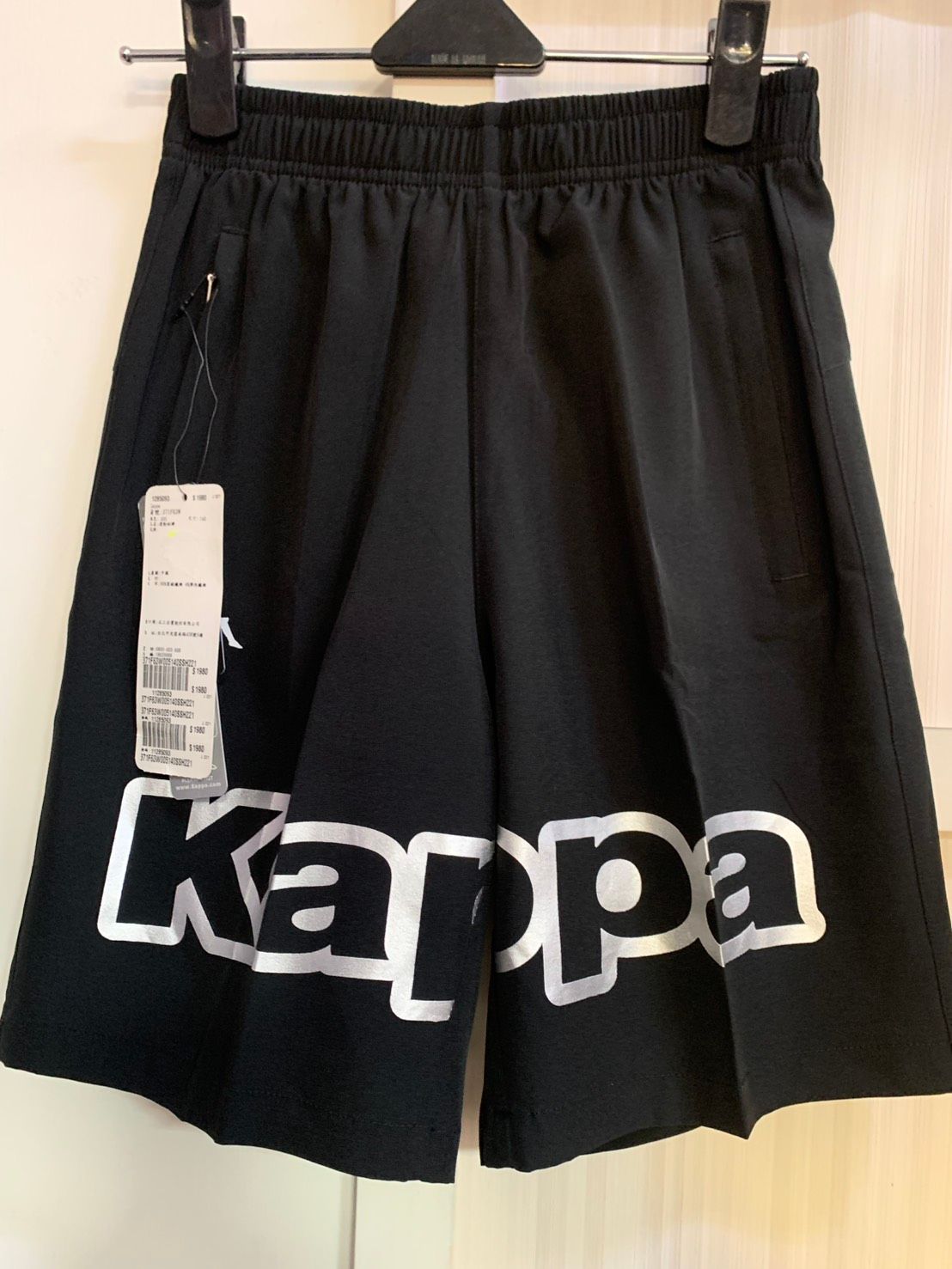 黑色 Kappa 運動短褲，帶有白色標誌和價格標籤。