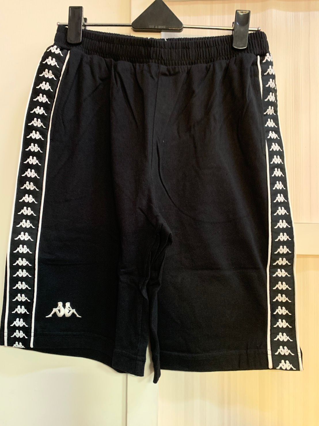 黑色 Kappa 短褲，兩側有白色標誌帶。