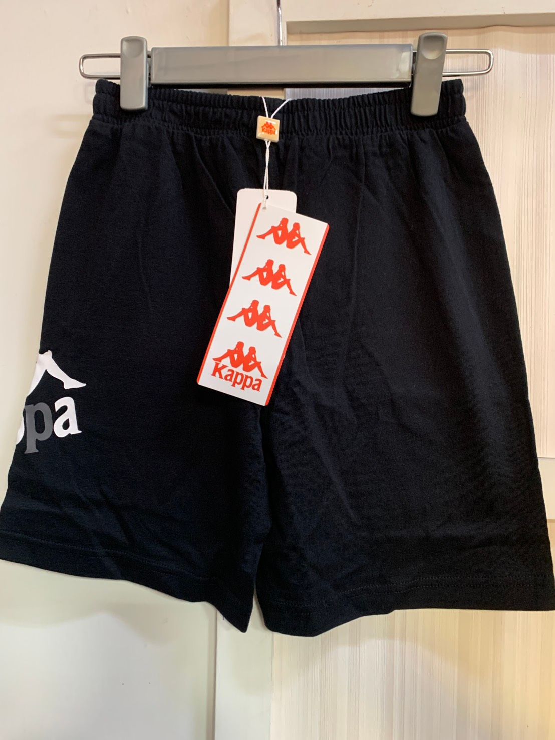 衣架上掛著白色標誌的黑色 Kappa 短褲。
