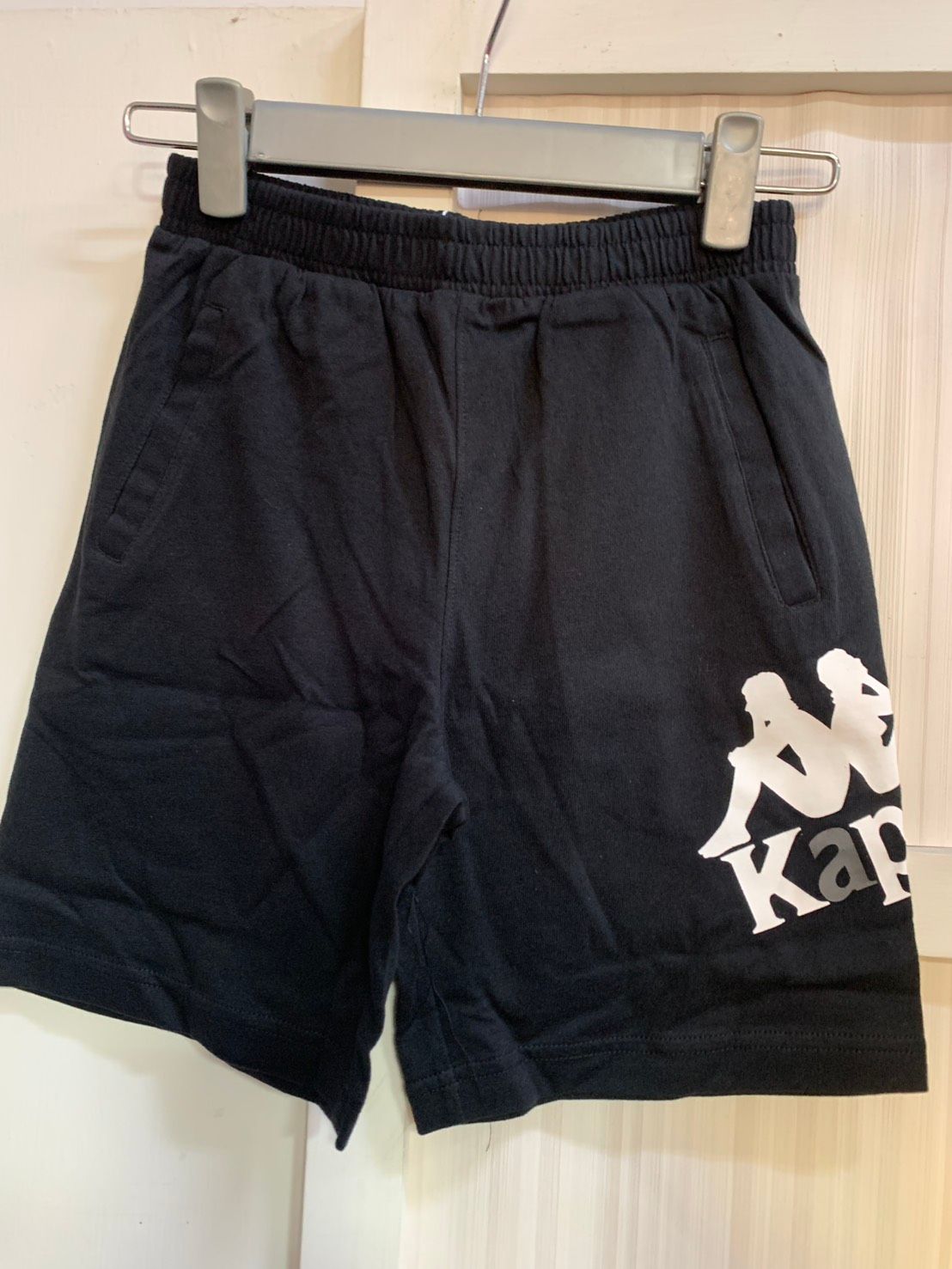 衣架上掛著白色標誌的黑色 Kappa 短褲。