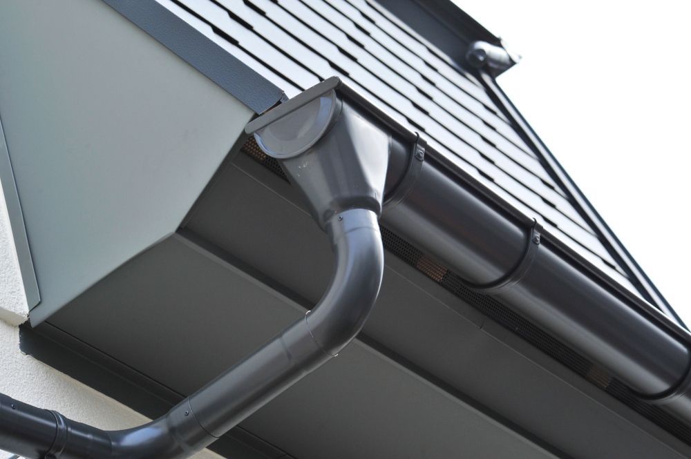 A Black Gutter On The Side Of A Building — Roof & Guttering Solutions In Saratoga, NSW