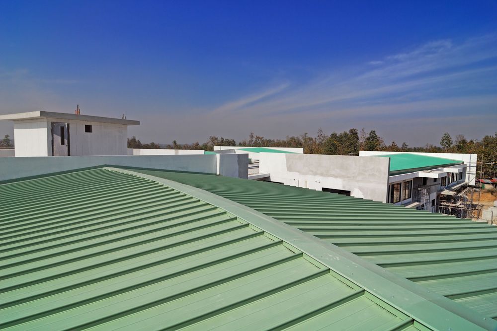 A Green Roof Of A Building With A Blue Sky In The Background — Roof & Guttering Solutions In Saratoga, NSW