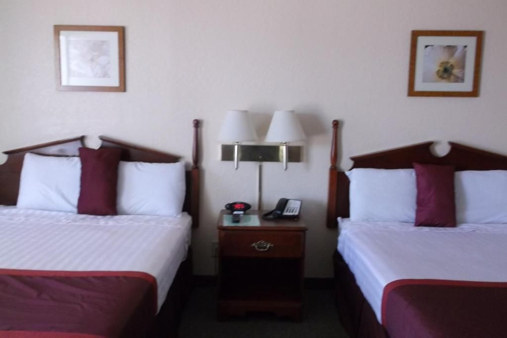 Hotel room with two twin beds, white linens, burgundy accents, and a nightstand between them