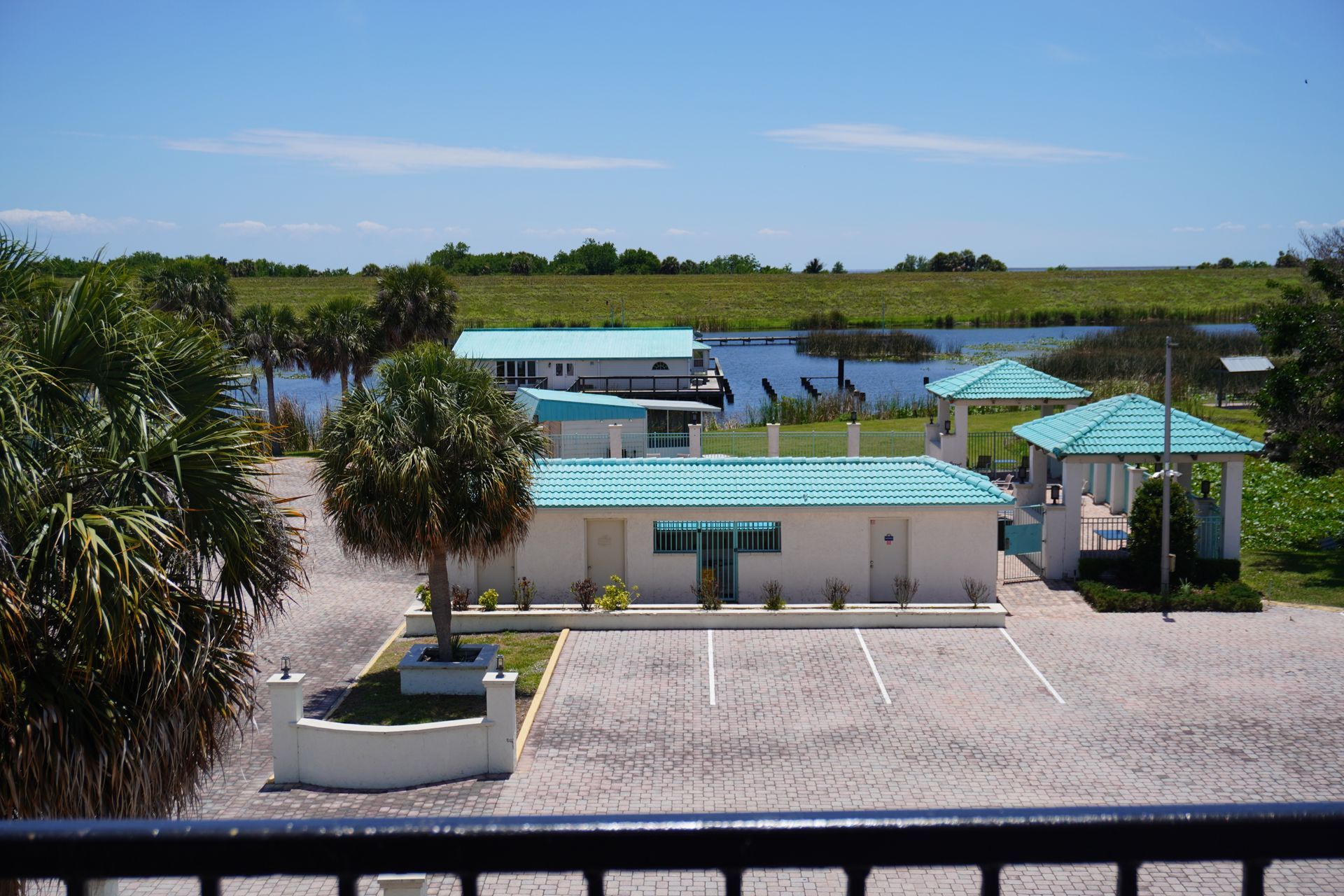 Small white waterfront building with teal roof and gazebo, overlooking a lake under a clear blue sky