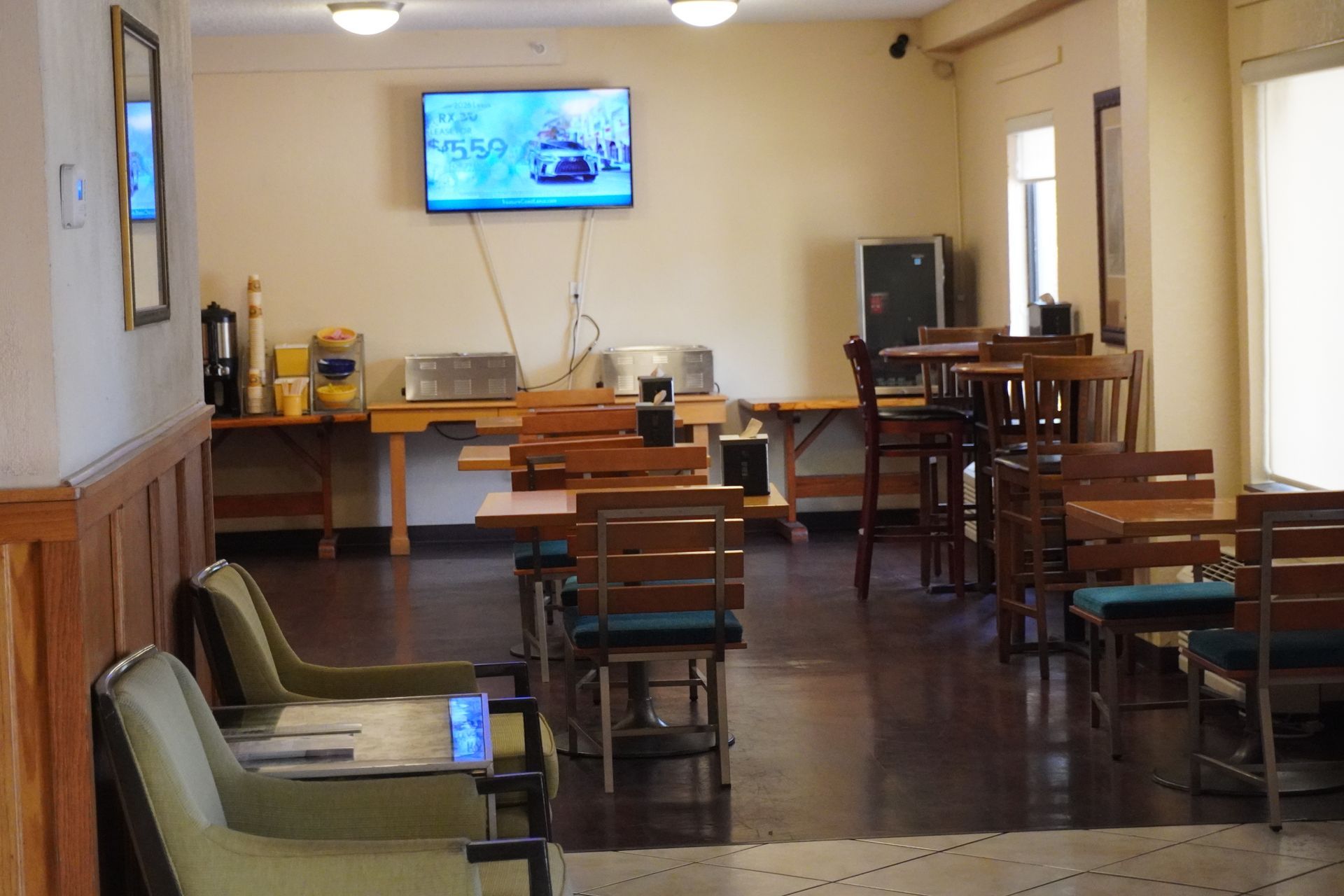 Empty cafeteria with chairs, tables, and a wall-mounted TV showing a sports broadcast.