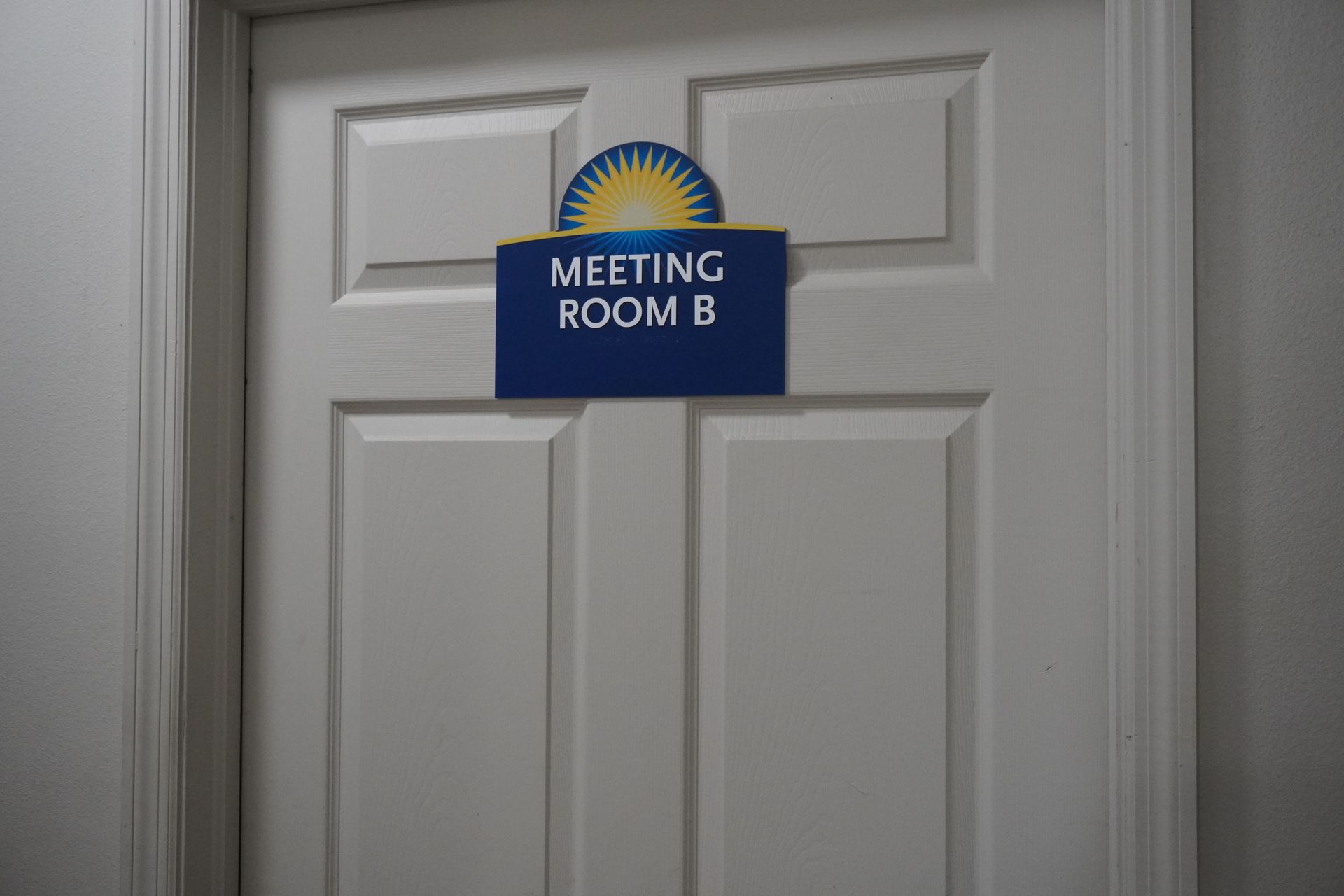 Blue “Meeting Room B” sign on a white door.