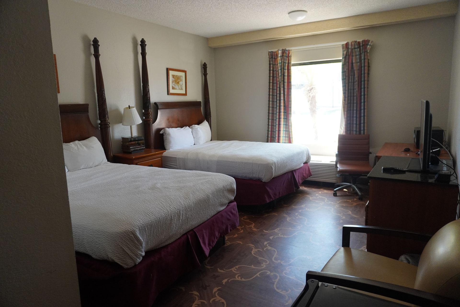 Hotel room with two beds, window, and TV on a dresser