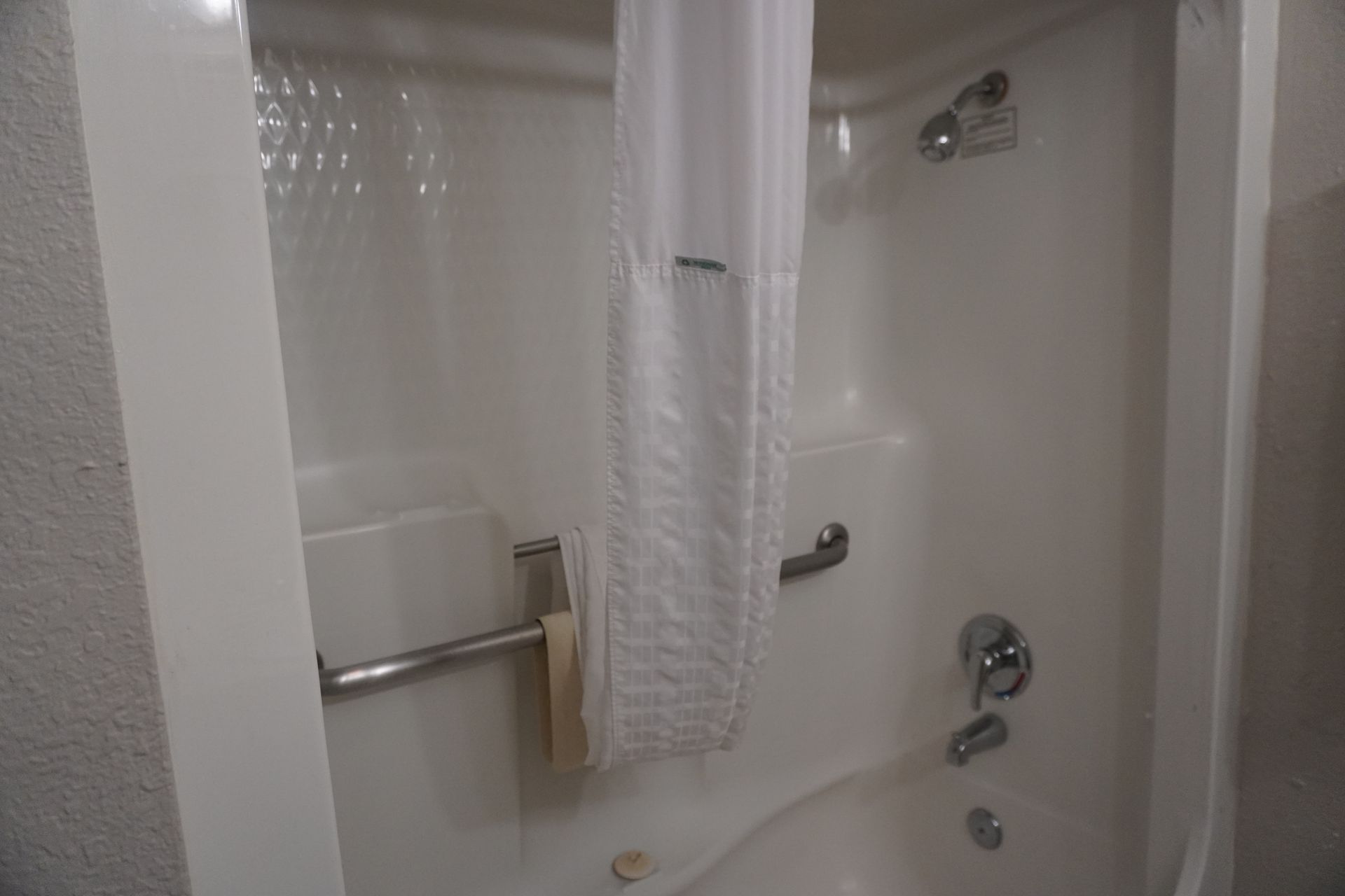 White bathroom/shower with tub, chrome grab bar, shower curtain, and wall-mounted showerhead