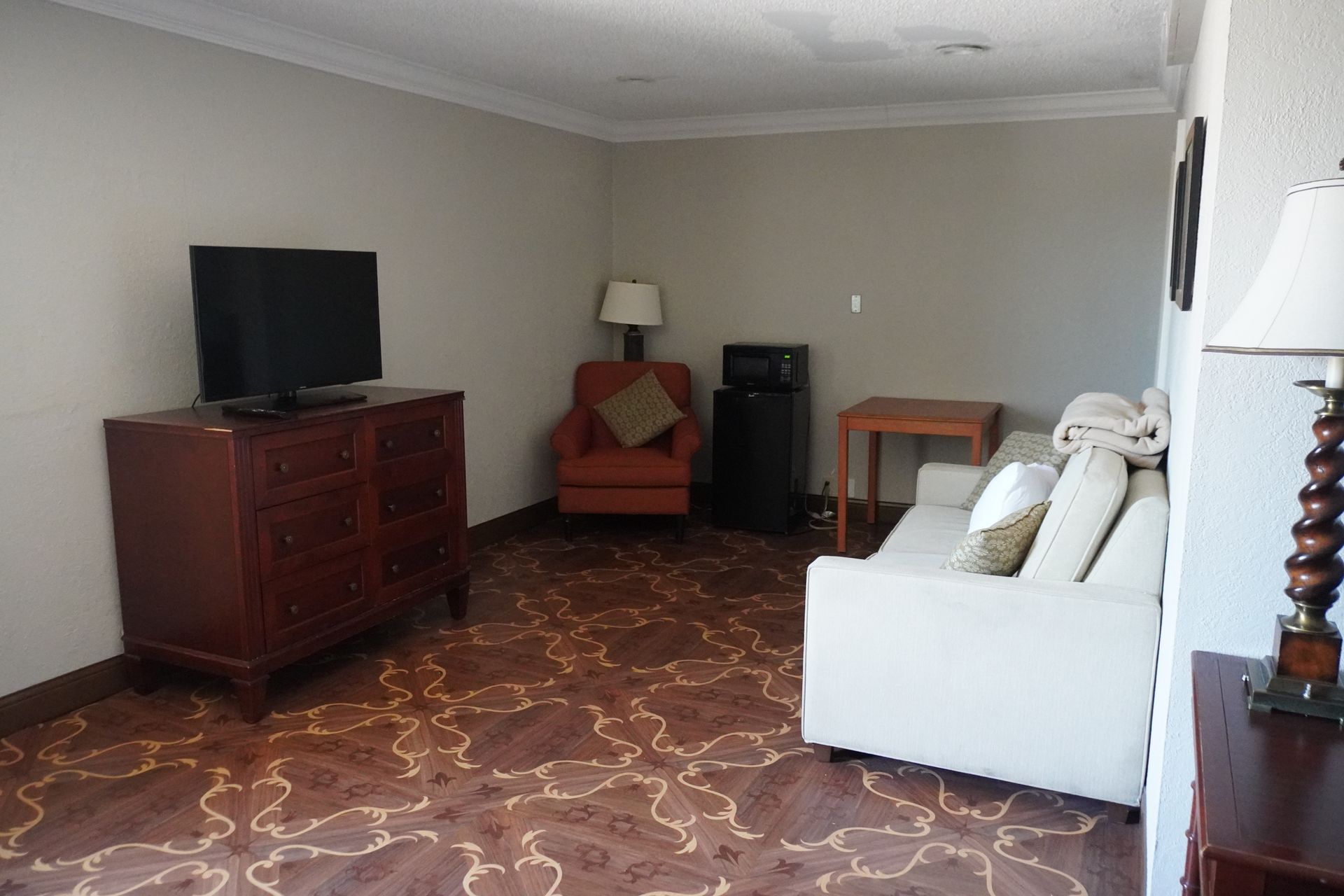 Living room with white couch, red armchair, TV cabinet, and patterned tile floor