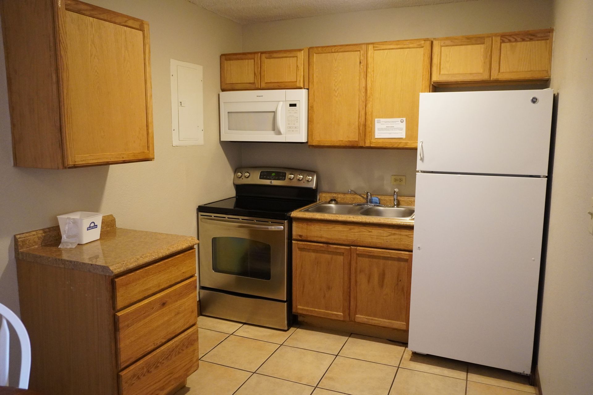 Small beige kitchen with white appliances, wood cabinets, and tiled floor