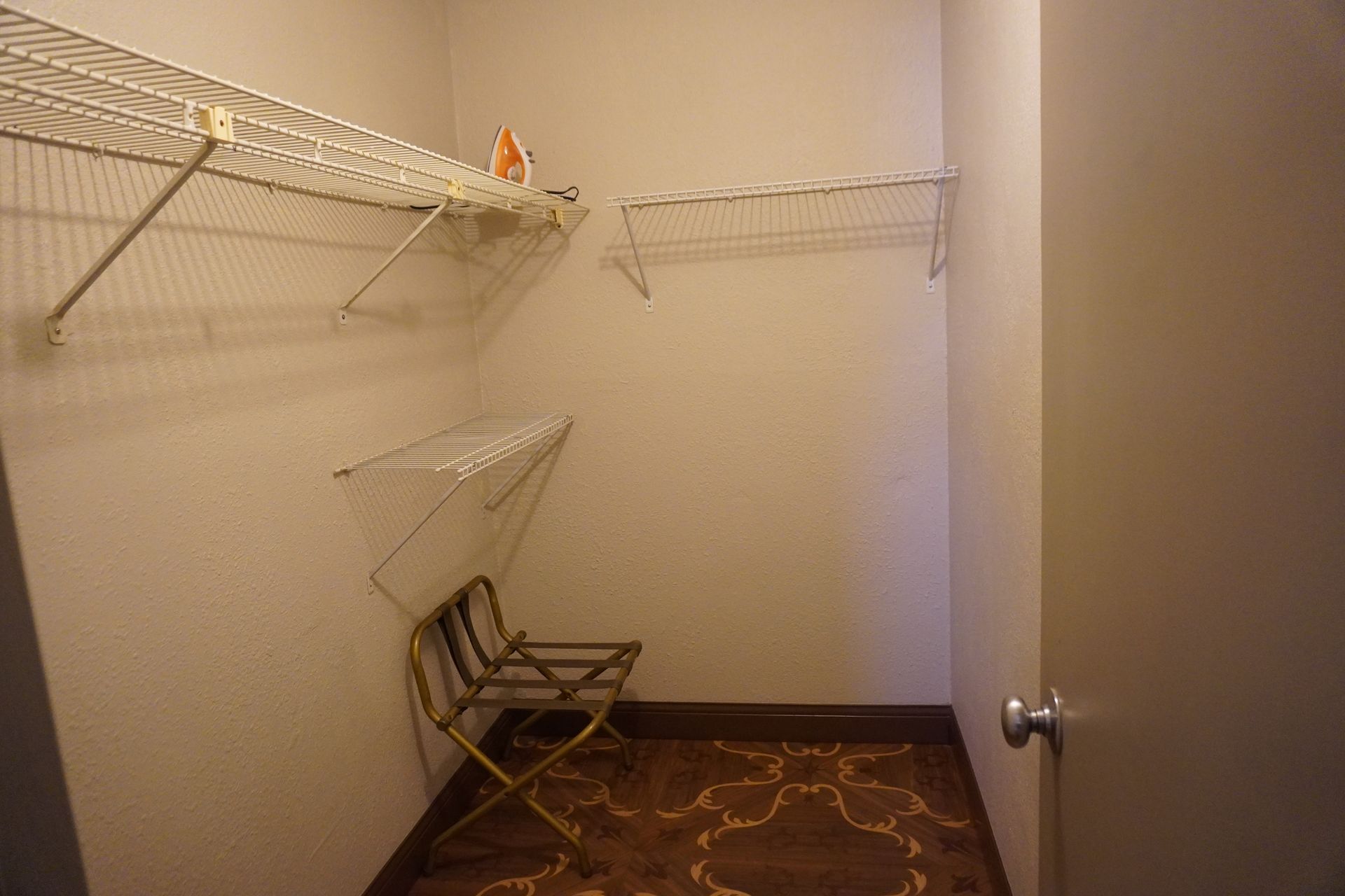 Empty walk-in closet with wire shelves, a folded chair, and a partially open door.