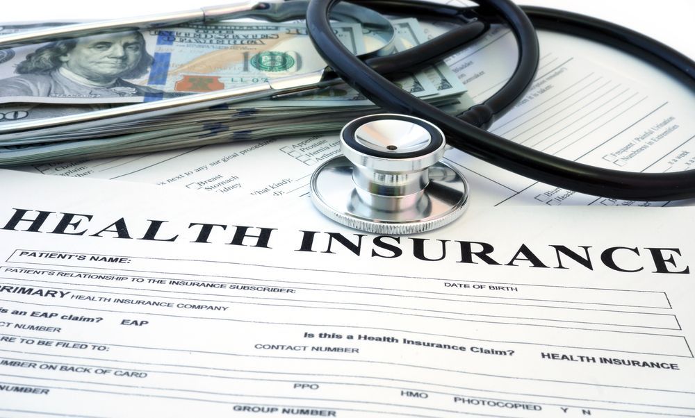 Health insurance form with stethoscope, money, and paperwork on a desk