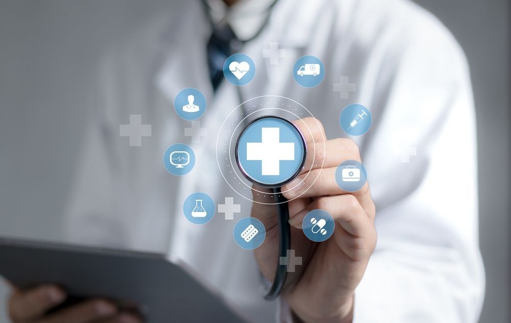 Doctor holding a tablet and touching a medical cross icon with digital healthcare symbols around it