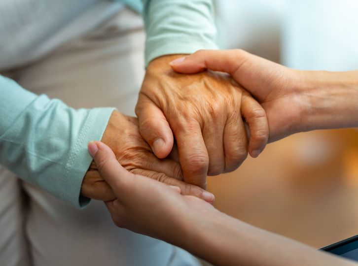Three hands gently holding together in a supportive gesture