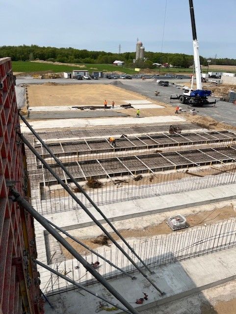 Construction site with concrete foundation, steel rebar, and a crane in an open field