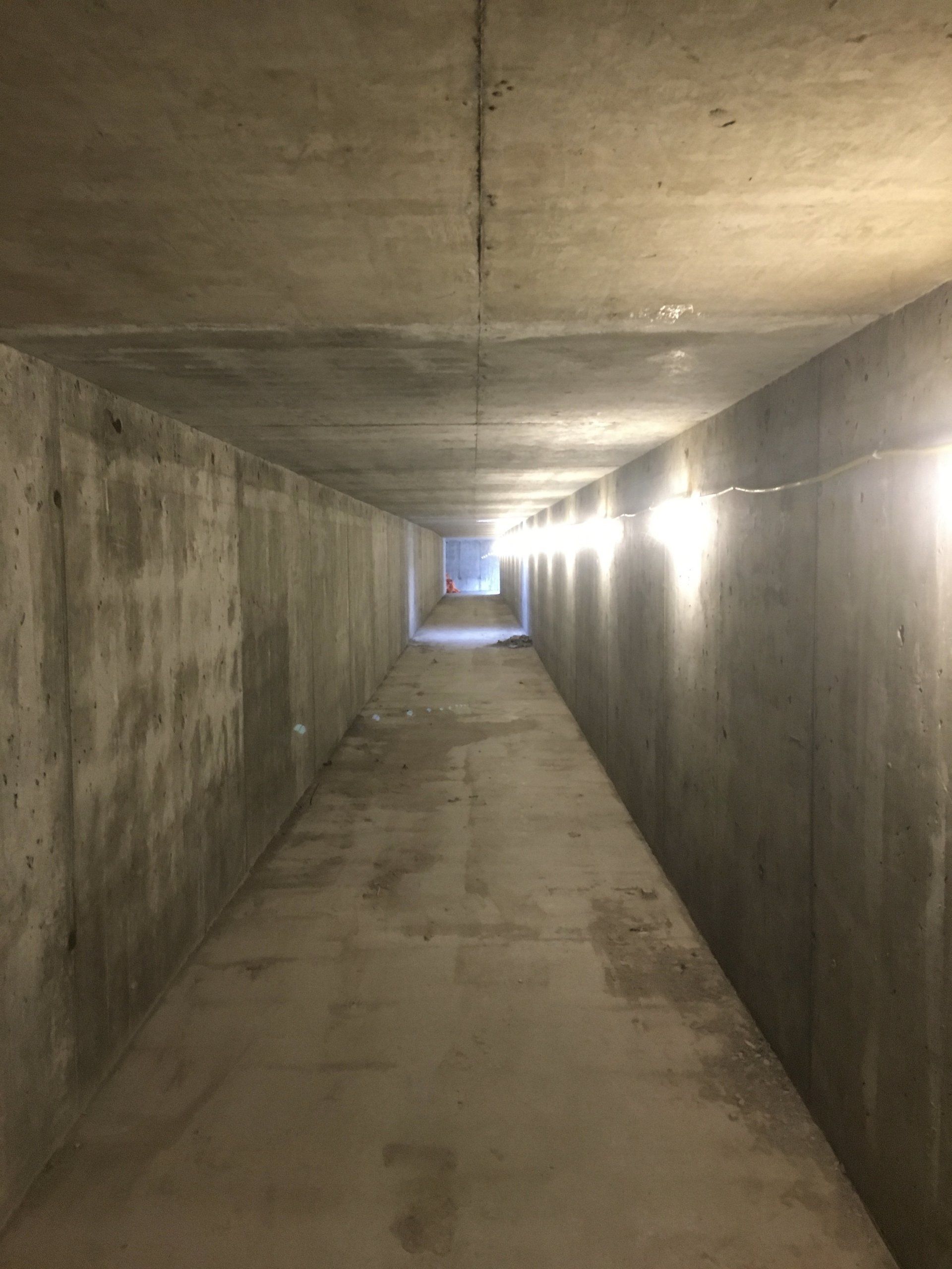 Concrete tunnel corridor with a bright light at the far end
