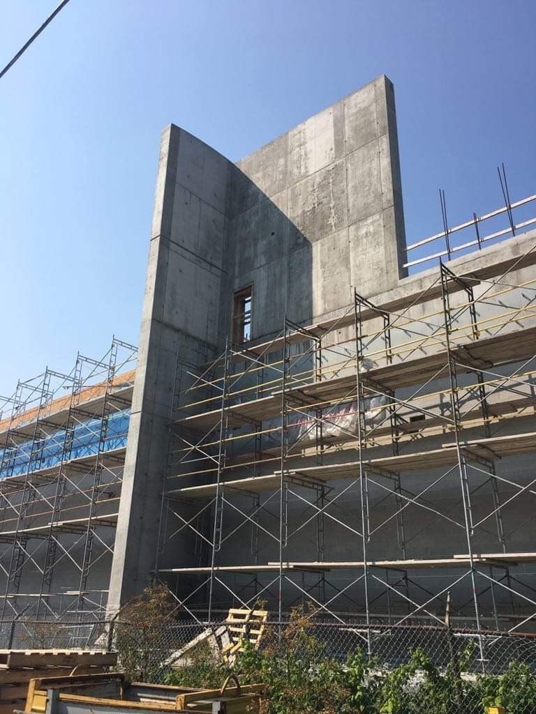 Concrete building under construction with scaffolding against a blue sky