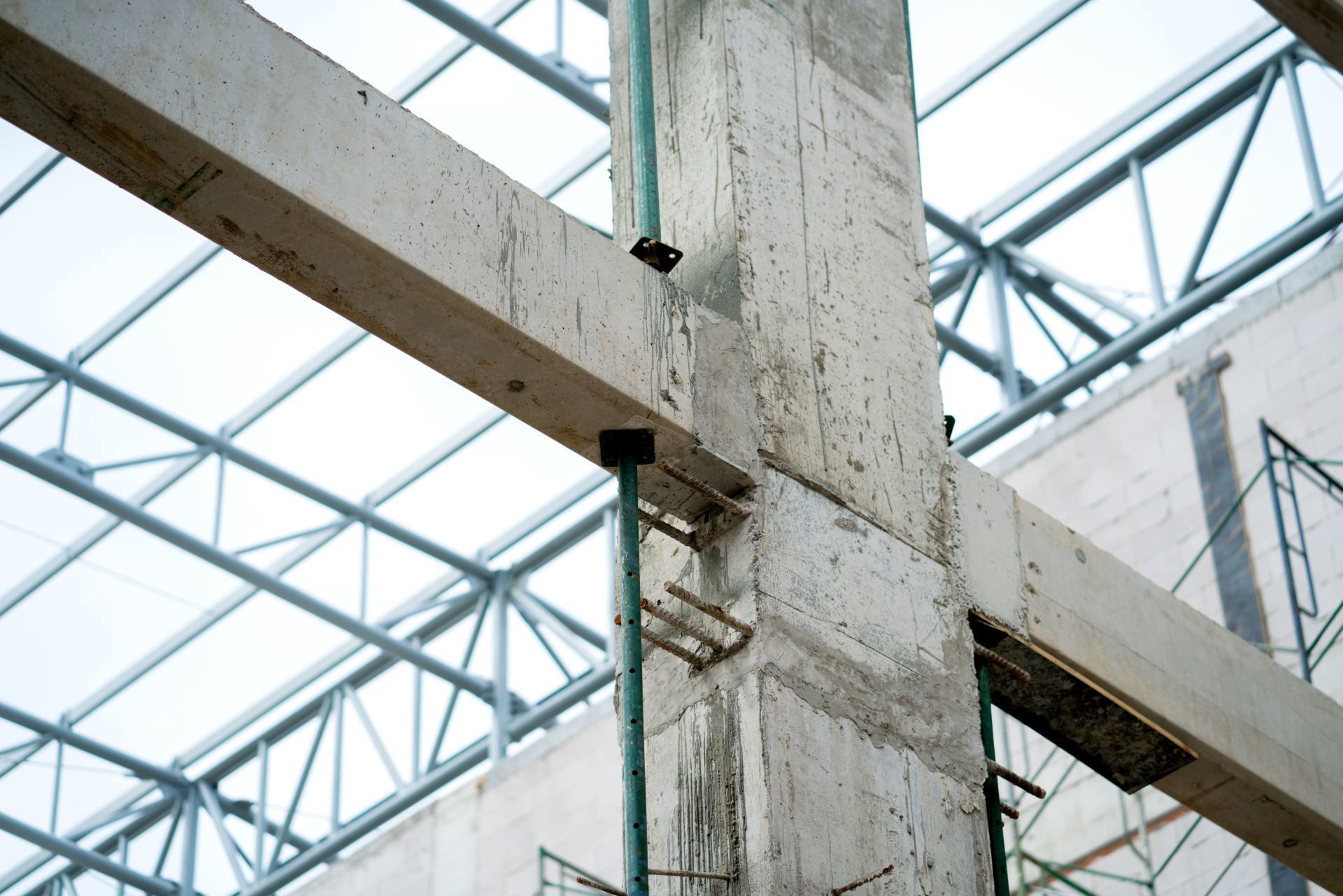 Concrete beams and steel trusses inside a glass-roofed construction site