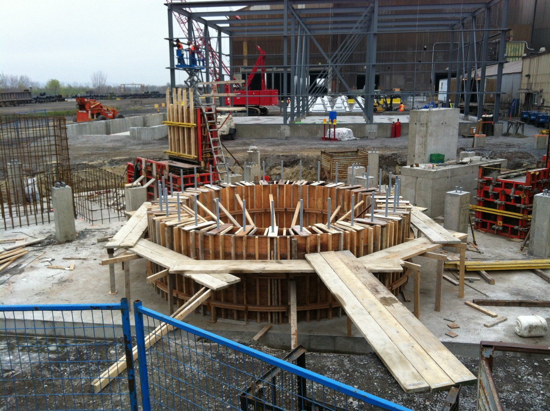 Construction site with rebar foundation formwork, wooden supports, and scaffolding under an unfinished structure