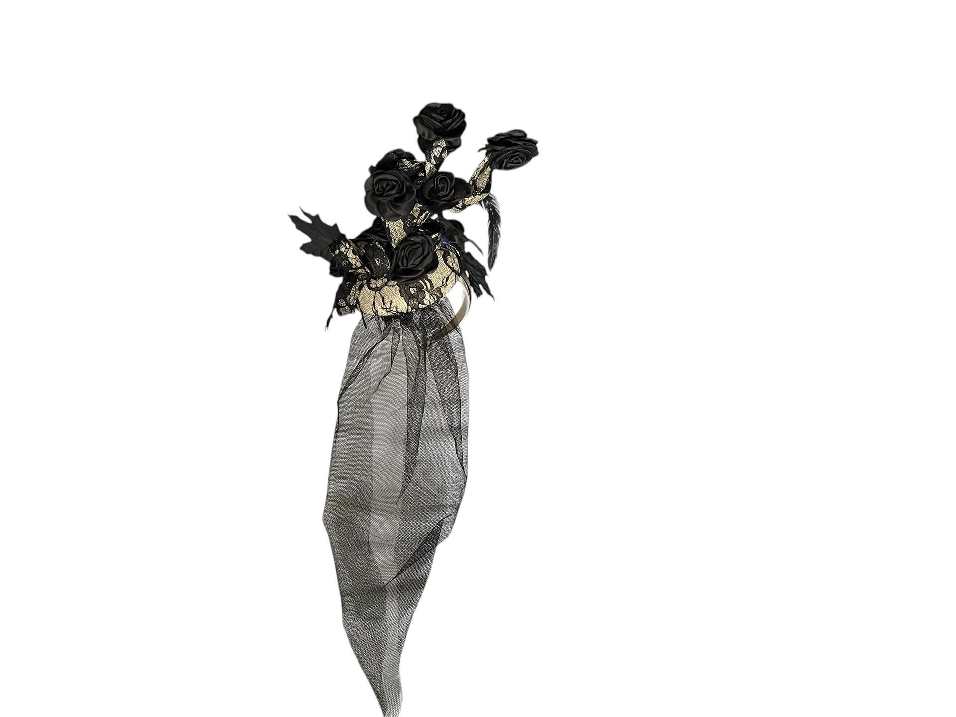 Portrait of a person in a lavender outfit with a black floral headpiece against a white background