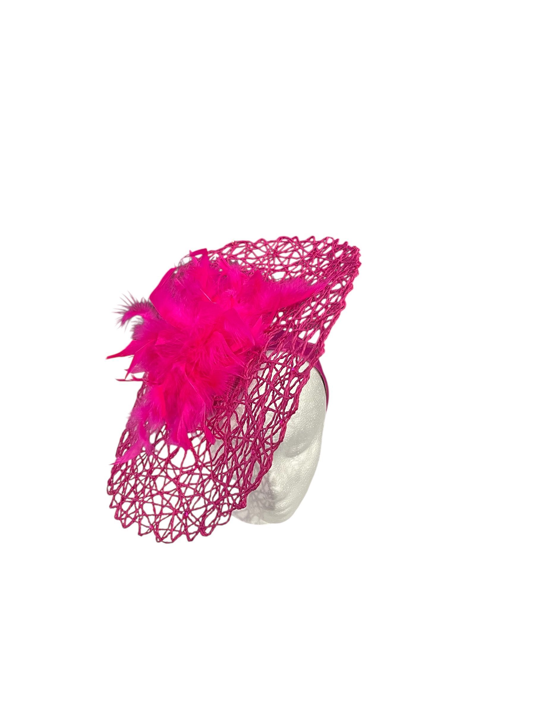 Hot pink, lace-like fascinator hat with a white base on a plain background