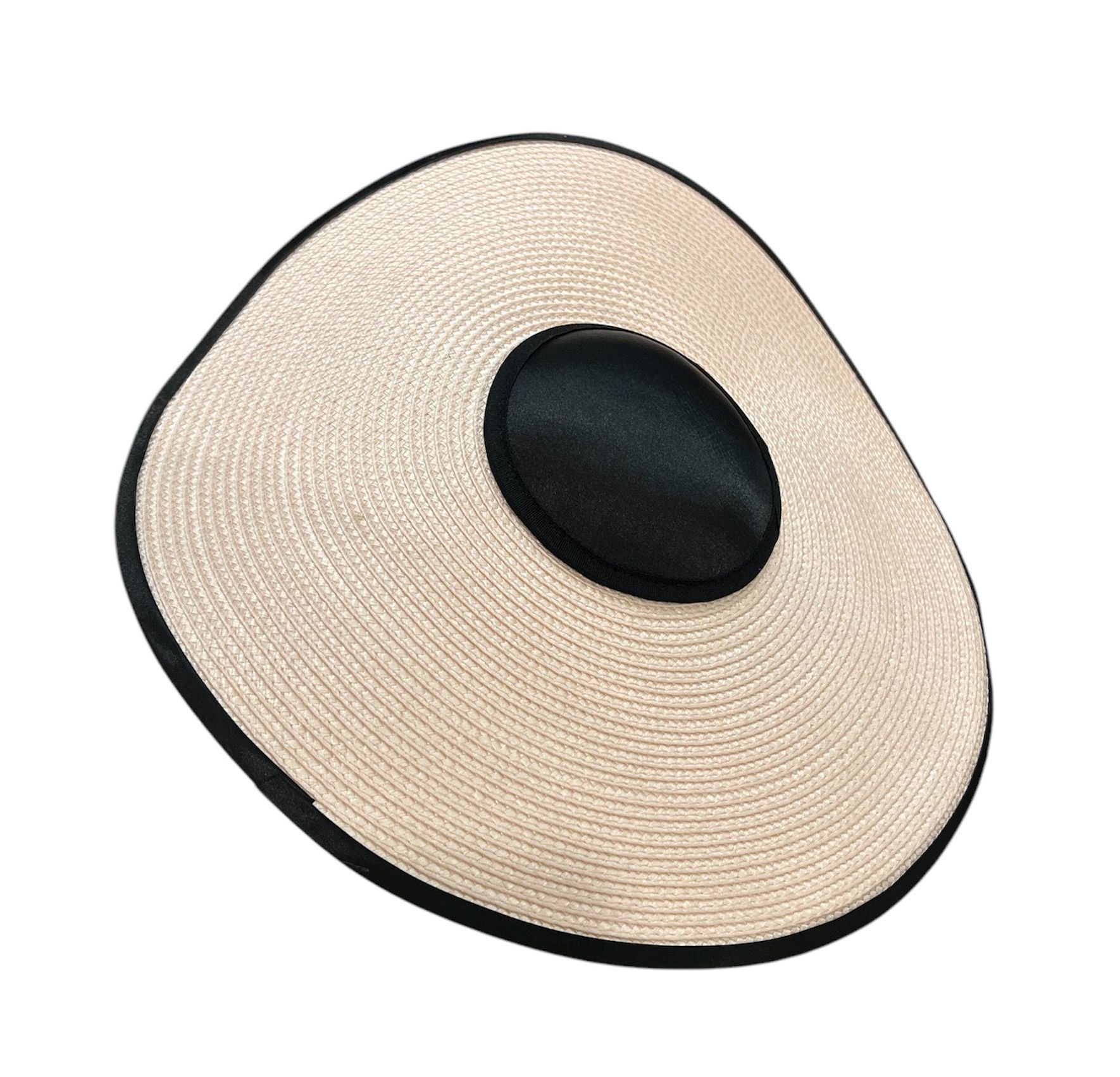 Beige woven sun hat with a black band and round black crown, viewed at an angle