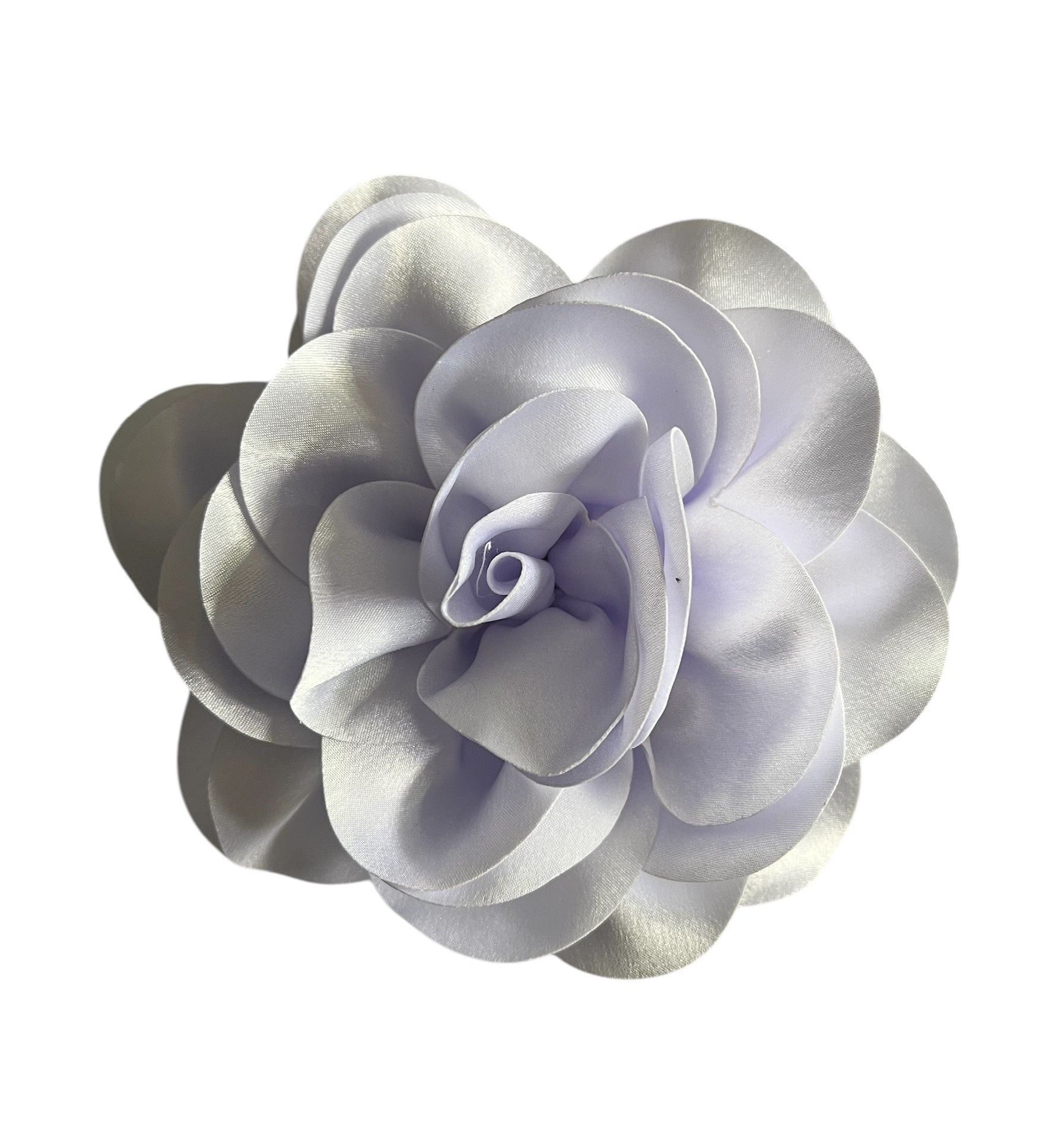 White satin flower brooch with layered petals and a pale purple center on a white background