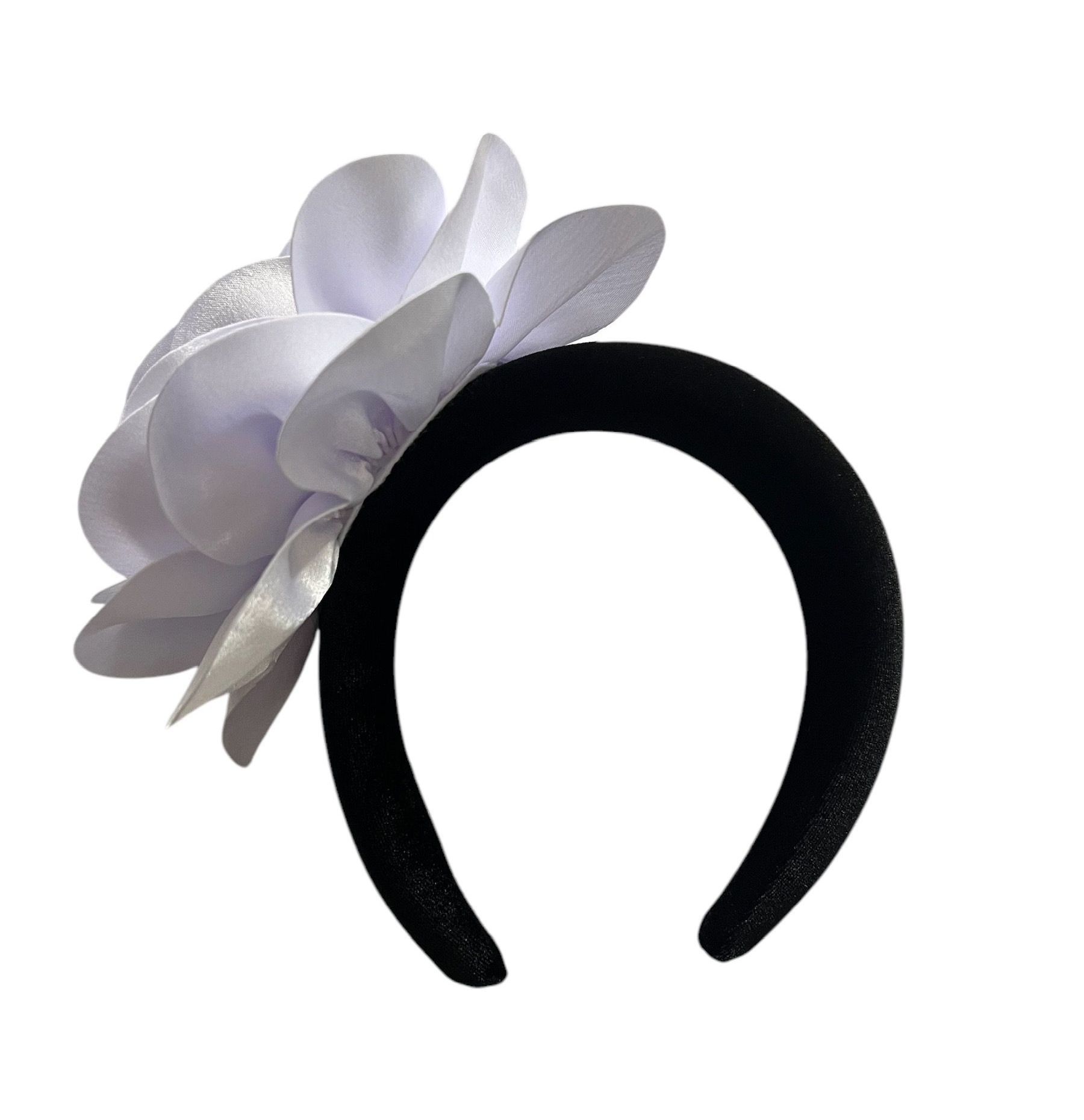 White satin flower brooch with layered petals and a pale purple center on a white background