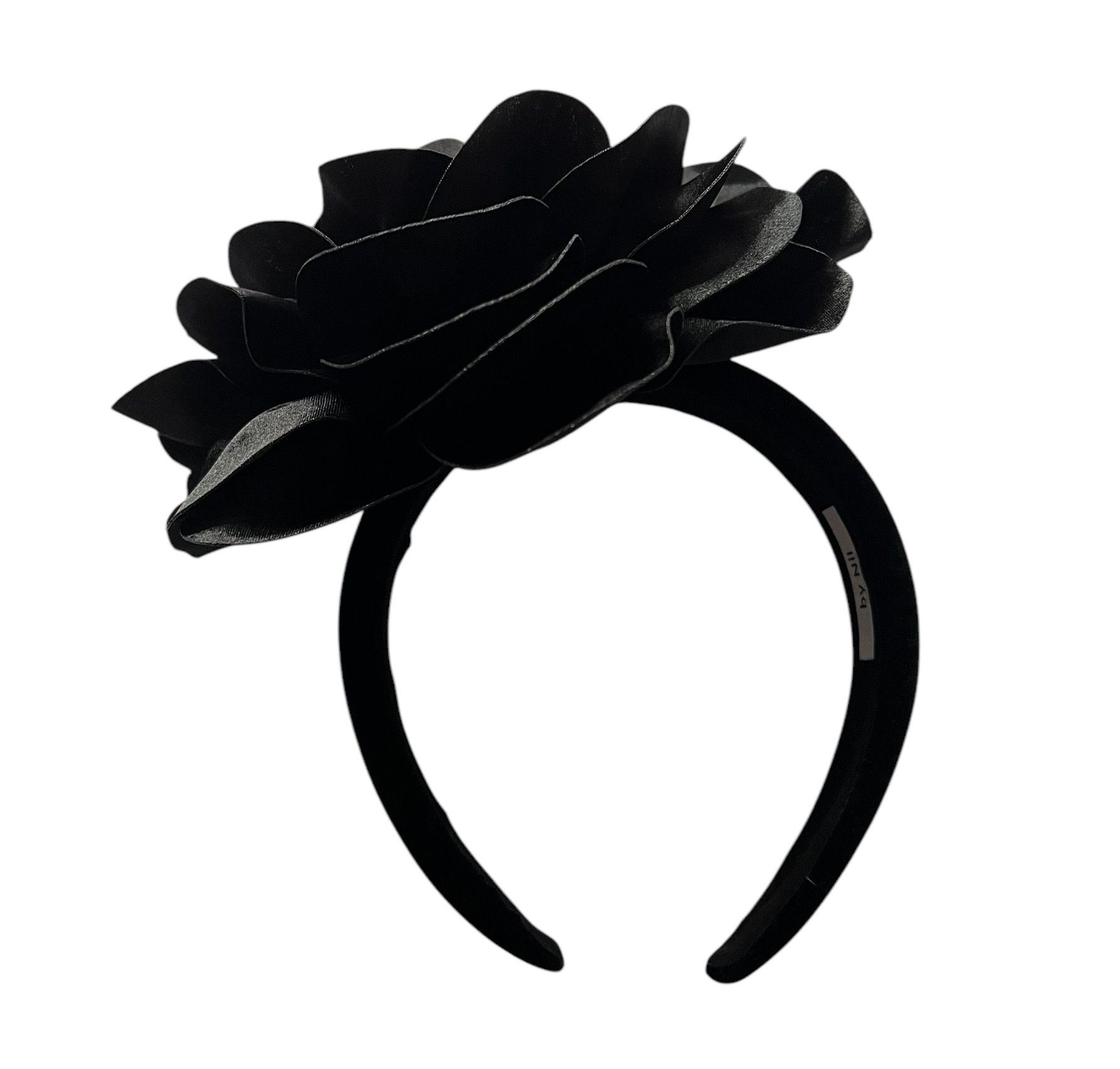Black fabric flower accessory with layered petals on a white background