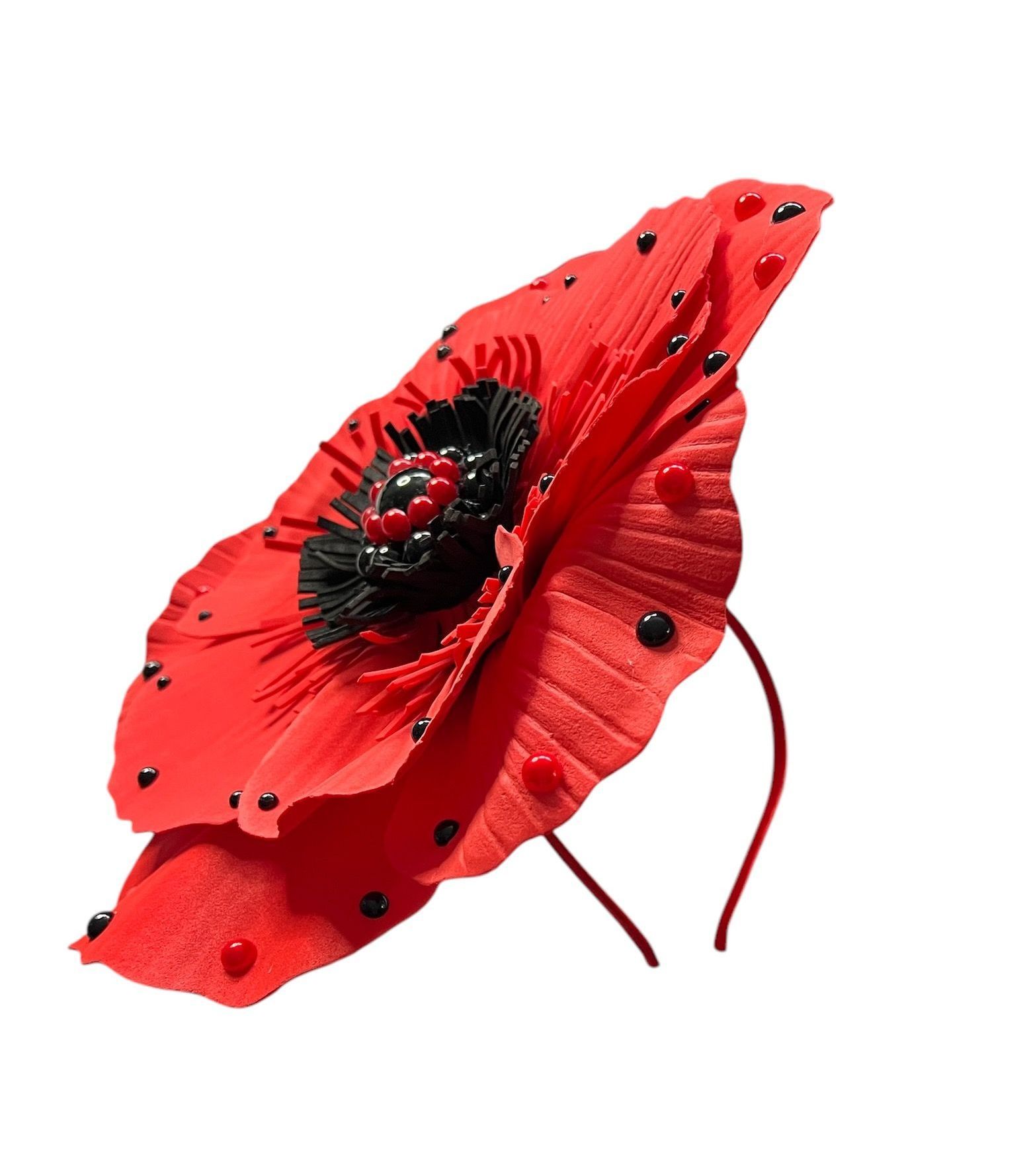 Red poppy flower with black center and small black accents on white background