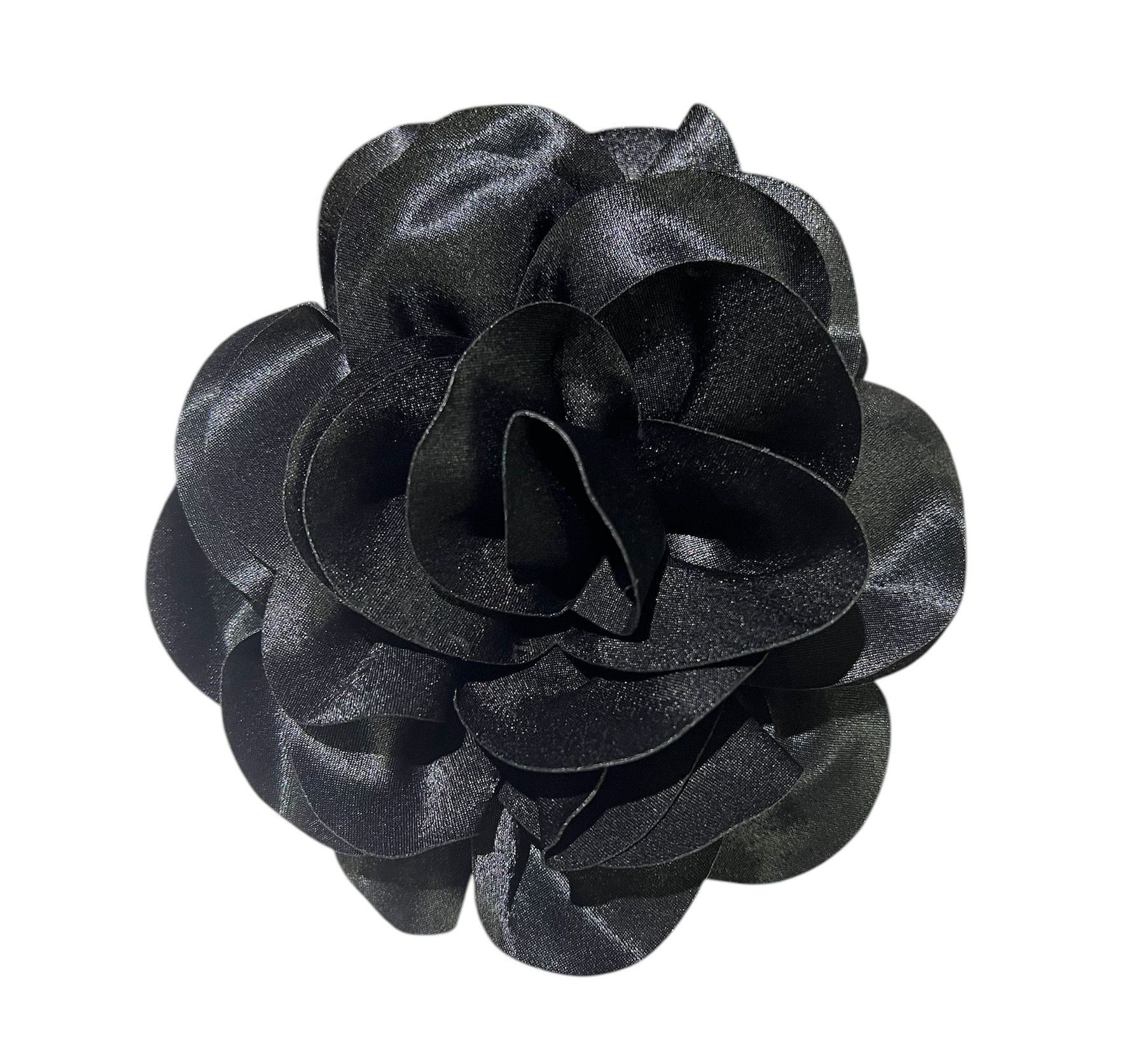 Black fabric flower accessory with layered petals on a white background