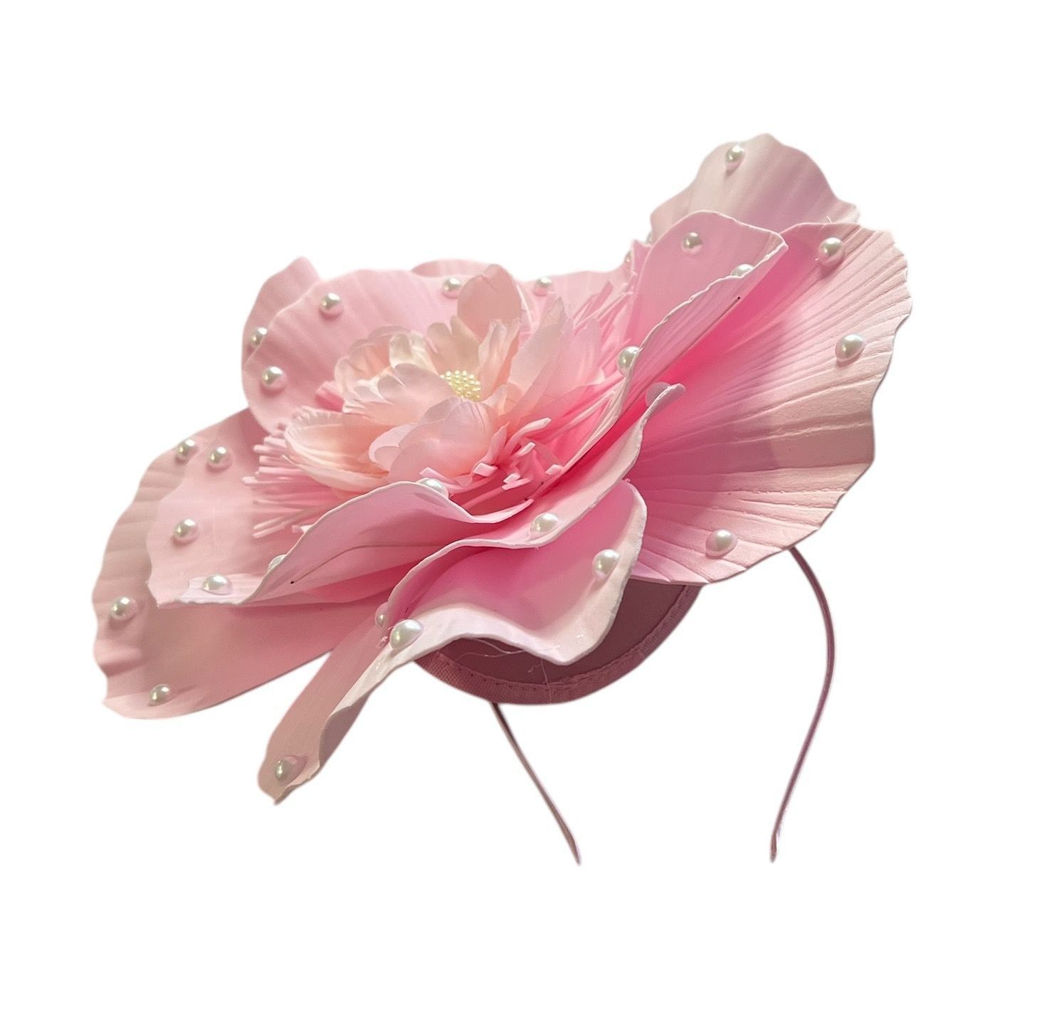 Pink flower with layered petals and pearl-like beads on a white background