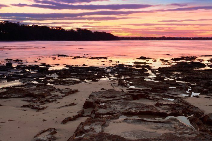 A Sunset Over A Body Of Water With Rocks In The Foreground — Sal's Excavations In Jervis Bay, NSW