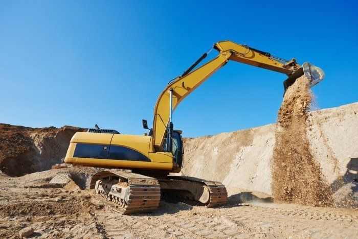 A Yellow Excavator Is Pouring Sand Into A Pile — Sal's Excavations In Jervis Bay, NSW