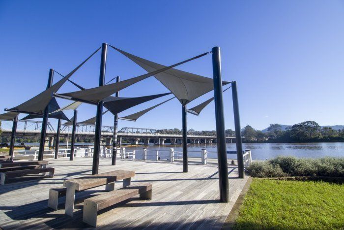 A Wooden Deck With Umbrellas And Benches Overlooking A Body Of Water — Sal's Excavations In Nowra, NSW