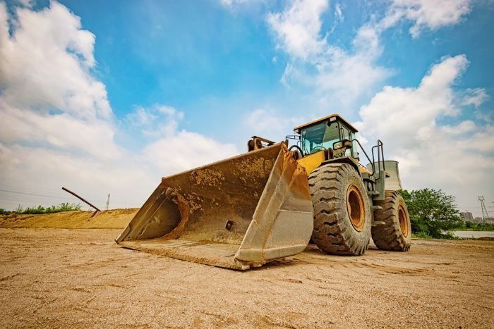 A Bulldozer With A Large Bucket Is Parked In A Dirt Field — Sal's Excavations In Vincentia, NSW